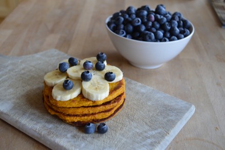 A photo of healthy pumpkin pancakes, topped with banana's and blueberries. The recipe is by That Healthy Kitchen