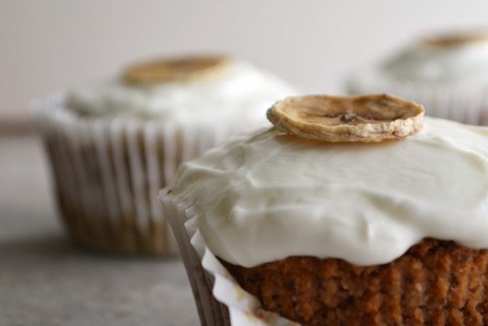 A photo of two healthy banana muffins with a Greek yogurt topping and dehydrated banana chips. Photo and recipe by That Healthy Kitchen