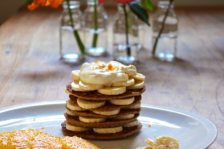 A stack of orange banana pancakes, topped with banana and orange slices. Recipe and photo by That Healthy Kitchen
