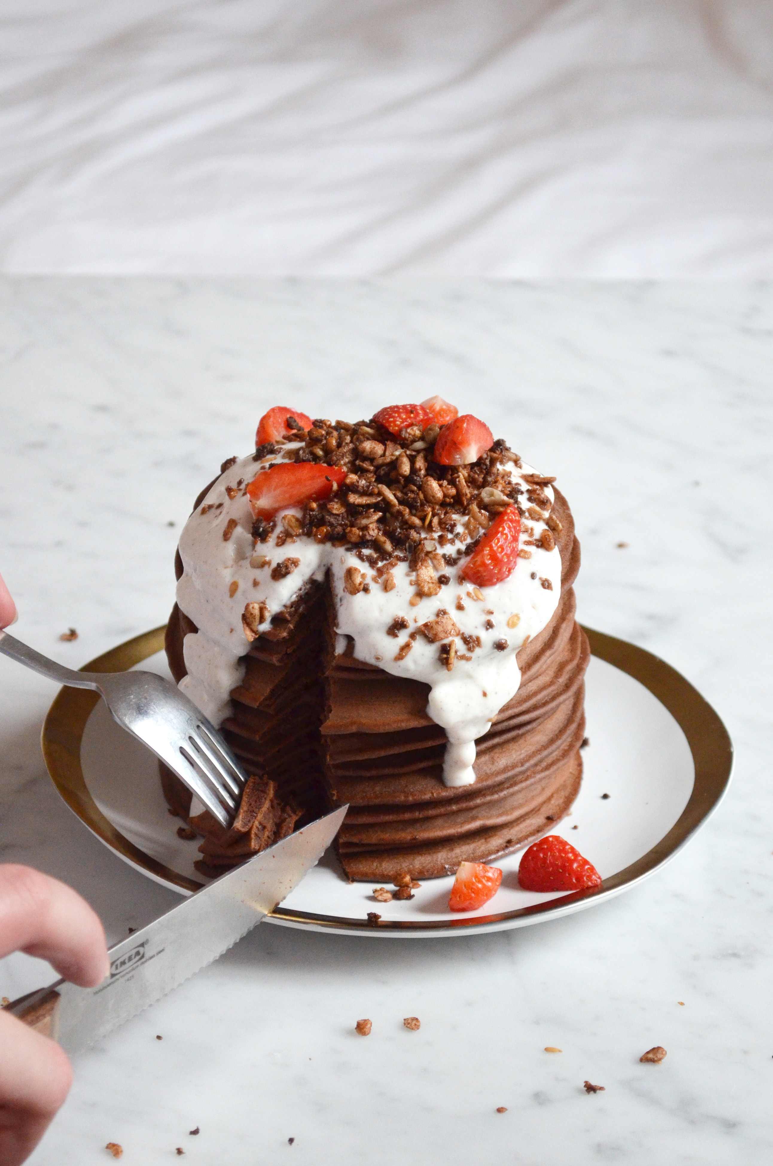A recipe for chocolate pancakes topped with a greek yoghurt vanilla cream, fresh strawberries and chocolate granola
