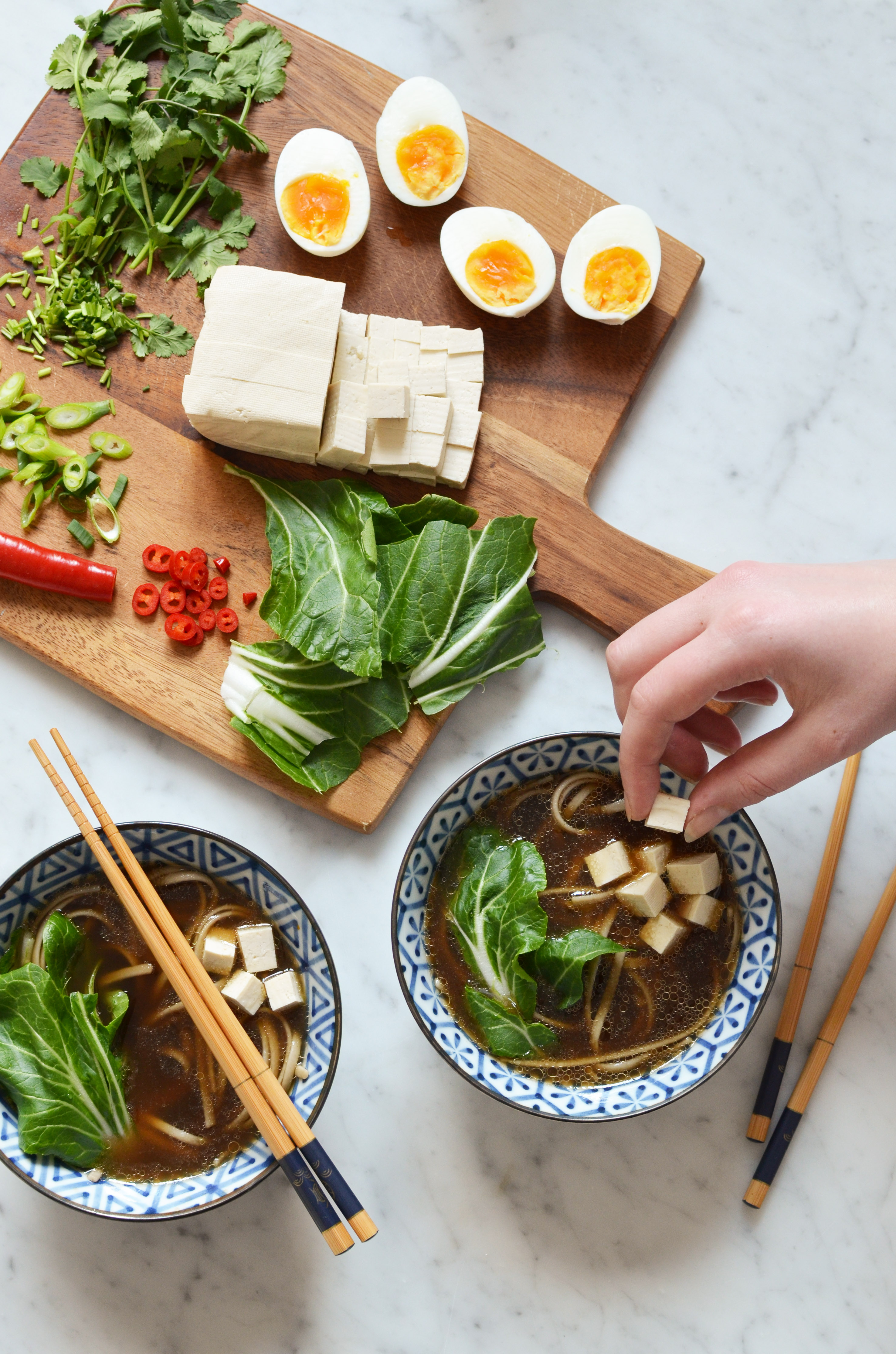 Recipe for spicy homemade ramen broth with all the toppings, including tofu, soft boiled eggs, fresh cilantro, red chili peppers, green onion, bok choy and buckwheat noodles. Gluten free!